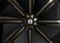 Close-up of a car wheel rim featuring a black and gold design with the Bentley logo at the center, showcasing the luxurious detail of a Bentley electric car.