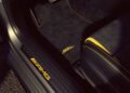 Close-up of the 2026 Mercedes-AMG CLA 45 S Final Edition interior, showing the AMG logo on the door sill, black floor mat with yellow trim, and sporty seat edge with yellow accent.