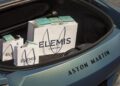 Shopping bags and boxes labeled "Elemis London" are placed in the open trunk of an Aston Martin car.