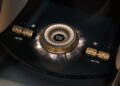Close-up of a Bentley EV center console featuring a metallic engine start-stop button and two climate control dials with "AUTO" settings.