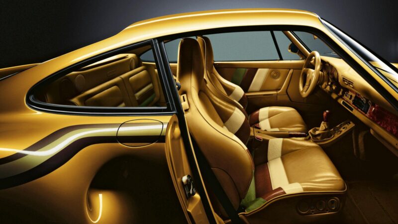 Side view of a gold sports car with the door open, revealing a tan and gold leather interior with striped seat accents and minimalist dashboard detailing, crafted as one of Porsche Exclusive’s rare factory one-off cars built to customer requests.