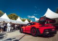 A red Porsche GT3 RS is displayed outdoors at Goodwood, surrounded by people and white tents under a clear blue sky.
