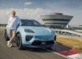A person stands next to a light blue Porsche Macan SUV with a "1,000,000" license plate on a racetrack near a modern Porsche building, celebrating the Millionth Macan milestone.