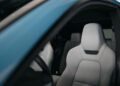 Close-up view of a modern Porsche Macan’s front passenger seat with light gray upholstery, seen through the open door of a blue vehicle, celebrating its Millionth Completion.