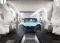In an automated automotive manufacturing facility, multiple robotic arms are painting a Porsche Macan car body, marking its millionth completion with precision and efficiency.