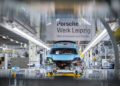 A partially assembled blue Macan on a production line at the Porsche factory in Leipzig, with a sign above reading "Porsche Werk Leipzig," marks the milestone of the Millionth Porsche produced here.