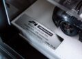Close-up of a plaque reading "McLaren F1 GTR 01R 1995 LeMans #59 30th Anniversary Race Finished Edition Limited 24/59" next to a model car, celebrating the legendary Lanzante team at Goodwood.