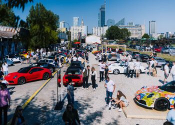 A large outdoor car show in Durham NC with numerous sports cars and many people walking, talking, and taking photos on a sunny day in an urban Luftgekhühlt 11 location.