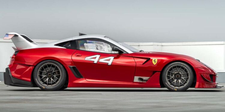 Red Ferrari race car with the number 44 and an American flag sticker on the rear, parked on concrete under a clear sky—just the kind of expensive car you'd find at an RM Sotheby's Monterey auction.