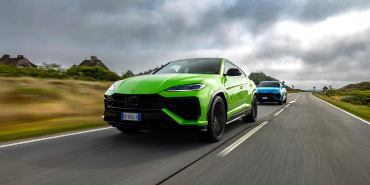 A bright green Lamborghini Urus SE leads a blue SUV on an empty, two-lane road near Sylt, with cloudy skies overhead and grassy shoulders—perfect for an exclusive event drive.