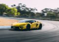 A yellow Lamborghini Temerario makes its dynamic debut, speeding around a curve on the official track with trees in the background.
