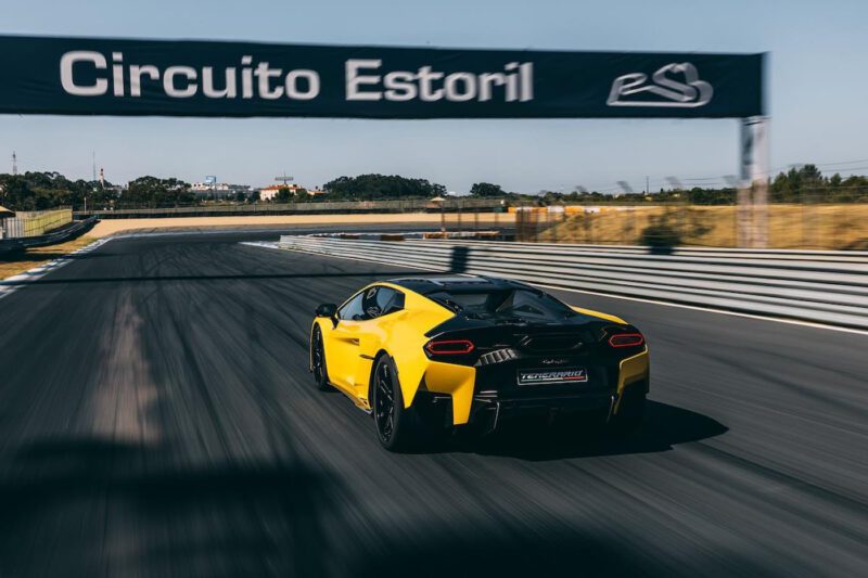 A yellow Lamborghini Temerario makes its dynamic debut on track at Circuito Estoril, passing under a sign with the circuit’s name.