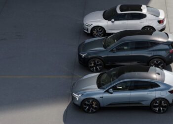Three modern cars, one white and two grey, are parked in a row on a concrete surface, viewed from above.