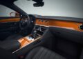 Luxury Bentley car interior featuring black leather seats, orange dashboard with chrome accents, Mulliner interior options, digital displays, and multifunction steering wheel.