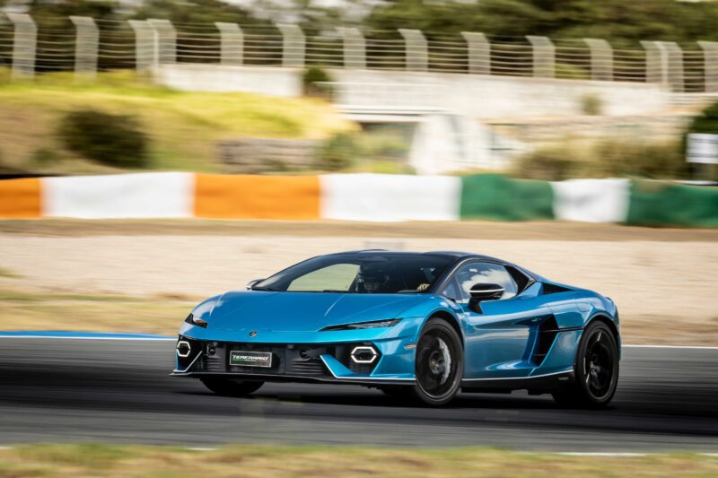 A blue Lamborghini Temerario speeds along a racetrack with blurred surroundings, highlighting its motion and power.