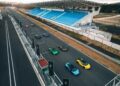 Aerial view of eight colorful sports cars, including the Lamborghini Temerario, lined up on a racetrack next to empty blue grandstands.