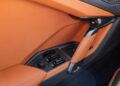 Close-up of a car's interior door panel featuring tan leather, a metallic door handle, and control buttons on carbon fiber trim—luxurious details reminiscent of the Lamborghini Temerario.