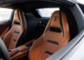 Interior view of a luxury sports car featuring two tan leather seats with black accents and the Lamborghini logo on the headrests, inspired by the V12 Revuelto for an exclusive driving experience.