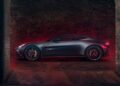 A 2026 Aston Martin Vanquish S sports car is parked in an industrial, dimly lit garage with exposed brick walls and red accent lighting.