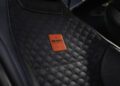 Close-up of a car seat featuring textured black leather upholstery, a prominent red Brabus Masterpiece badge, and sleek detailing—a testament to BRABUS excellence found in high-performance cars like the AMG GT.
