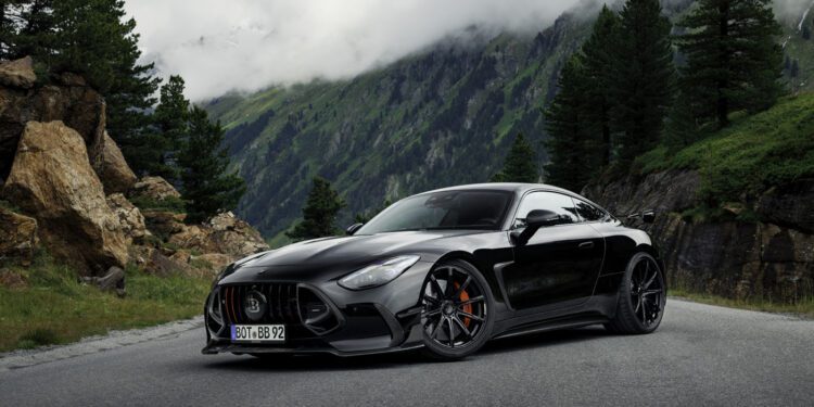 A BRABUS AMG GT hybrid supercar is parked on a mountain road, surrounded by trees and rocky cliffs with misty mountains in the background.