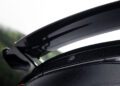 Close-up view of a black carbon fiber rear spoiler with raindrops on its surface, attached to a BRABUS-tuned car featuring a "B" emblem.