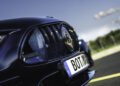 Close-up of the front grille and headlight of a dark blue Brabus car with a German license plate reading "BOT BR." The car is parked on pavement with a blurred outdoor background.