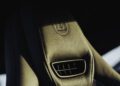 Close-up view of a BRABUS leather car seat in Deep Blue, with detailed stitching and an embossed logo, featuring a built-in ventilation vent, illuminated by natural light.