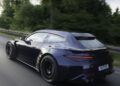 A Deep Blue BRABUS Rocket GTS sports car with a wagon body style drives on a road next to trees, captured in motion from the rear left side.
