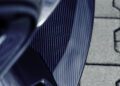 Close-up of a Deep Blue carbon fiber BRABUS Rocket GTS front splitter with striking reflections, positioned next to interlocking stone pavement.