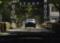 A car accelerates from the starting line on the Goodwood Hillclimb track, with hay bales and trees lining the route under a "START" banner, evoking memories of record runs like that of the Bentley Bentayga Speed.