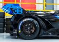Close-up view of the rear wheel and fender of a blue and black #001 of 40 Track-Only Bugatti Bolide with Michelin Pilot Sport tires in a garage, set for auction debut at Pebble Beach.