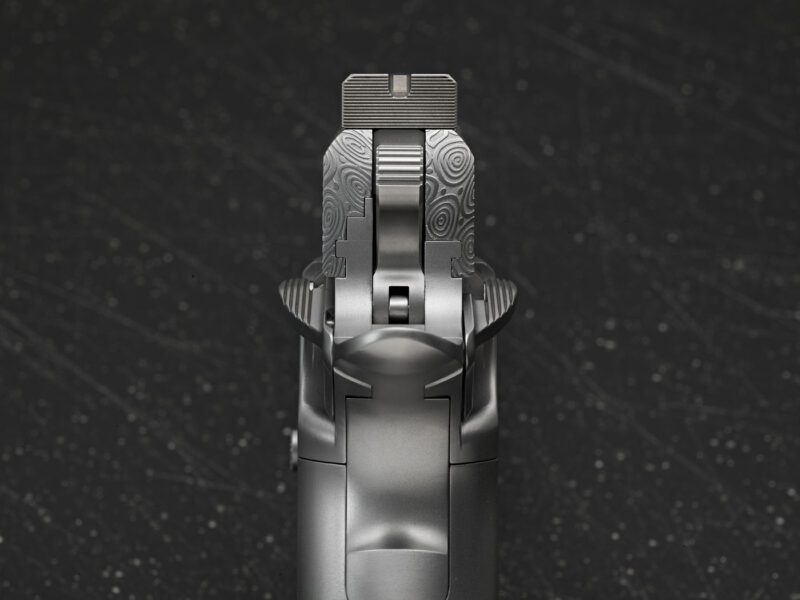 Close-up view of the rear sight and top of a Cabot Guns pistol against a dark, speckled background, capturing the legacy of precision craftsmanship.