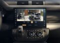 Close-up of a Defender’s digital dashboard screen displaying a rearview camera feed with parking guidelines and various control buttons below, highlighting recent design updates.