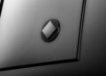 Close-up of an OCTA Black matte surface, inspired by the 2026 Land Rover Defender, with a raised diamond-shaped button at the center, surrounded by straight and beveled panel lines.
