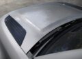 Close-up view of a Defender’s hood and windshield, featuring black air vents on both sides and subtle reflections of trees—a showcase of recent design updates.