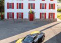 A black and yellow Tailor Made Daytona SP3 Ferrari is parked in front of a white building with red shutters and a tiled roof, ready to turn heads at the Car Week Charity Auction.