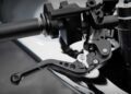 Close-up view of a motorcycle handlebar featuring a black adjustable brake lever and control components, showcasing the futuristic aluminum sculpture aesthetic of this limited edition rideable sculpture.