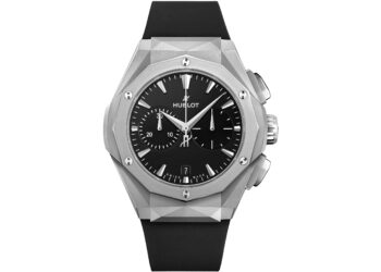 A silver Hublot wristwatch with a black dial, geometric bezel, chronograph subdials, and black rubber strap is shown against a white background—a striking choice among the best luxury watches.
