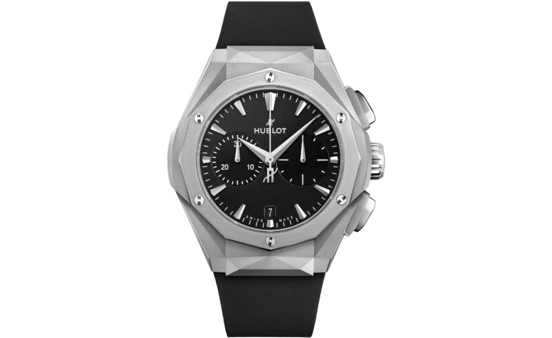 A silver Hublot wristwatch with a black dial, geometric bezel, chronograph subdials, and black rubber strap is shown against a white background—a striking choice among the best luxury watches.