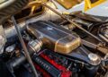 Close-up view of a Ferrari engine with the hood open, showing detailed components and the Ferrari logo on the engine cover—a nod to iconic models like the Ferrari Enzo.