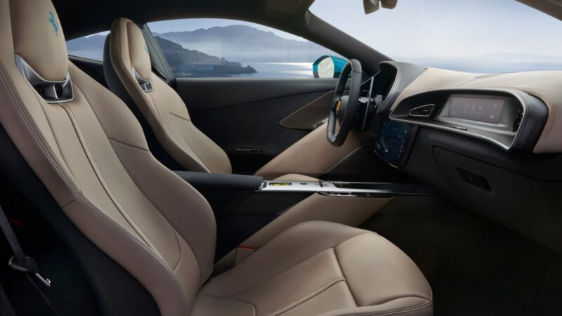 The interior of a modern luxury car with tan leather seats, a digital dashboard, and a view of the coast through the windows hints at the sophistication seen in recent Ferrari Amalfi models.