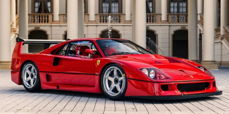 A red Ferrari F40 LM is parked on a cobblestone driveway in front of an ornate building with columns and arches, reminiscent of the elegance seen at RM Sotheby's Monterey Auction.