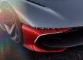 Close-up of the front left side of a futuristic red and gray sports car, inspired by the California Corvette: GM's Pasadena Studio Showcases One-Off Hypercar Concept, highlighting its sleek headlight, angular bodywork, and unique wheel design.