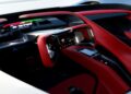 Futuristic car interior featuring a red and black steering wheel, a digital dashboard, and a touchscreen control panel inspired by the California Corvette: GM's Pasadena Studio Showcases One-Off Hypercar Concept.