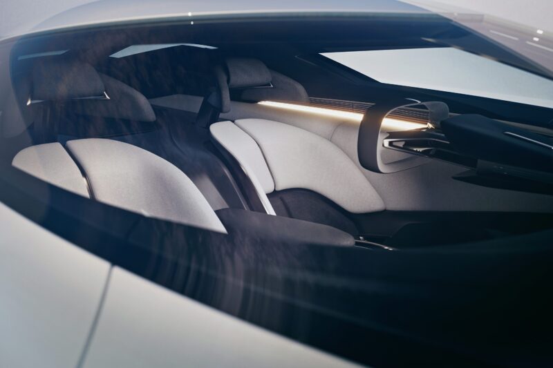 A view through the windshield of a modern Corvette, showing minimalist, light gray interior seats and a sleek, futuristic dashboard design that reflects the American icon's future design.