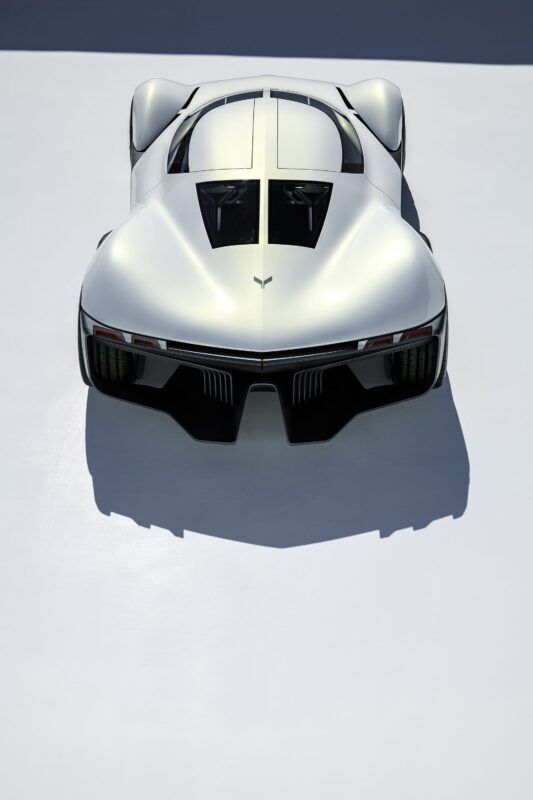 A sleek, futuristic white Corvette sports car is photographed from above, highlighting its aerodynamic shape and black accents against a minimalist, light background—a true future design and American icon.