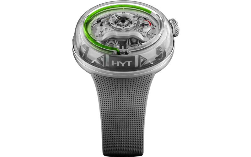 A modern wristwatch with a transparent dial, green fluid time display, metallic case, and textured black rubber strap. The brand "HYT" on the dial marks it as one of the best luxury watches for style and innovation.