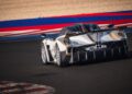 A silver and black Pagani sports car takes a corner on a racetrack with red, white, and blue painted curbs during hillclimb runs at Goodwood FoS 2025.