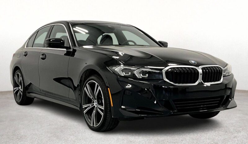 A black BMW sedan is parked on a light gray surface in front of a plain white background, highlighting one of the best lease deals available for those seeking a new car lease.